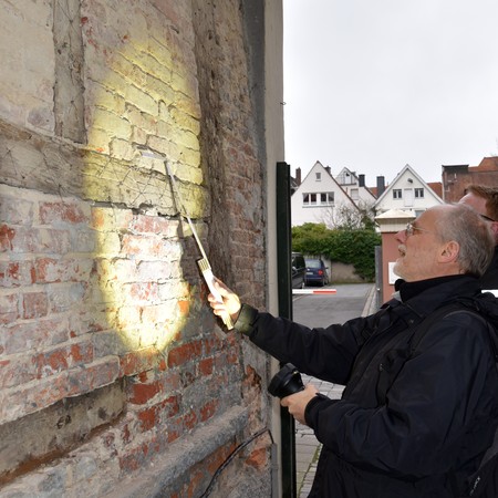 Bauforscher betrachtet Fassade im Streiflicht