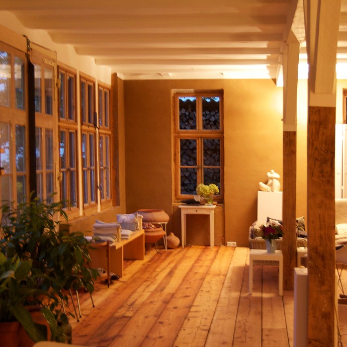 Warme Farben, Holzboden und weiße Decken prägen den Wohnraum (vergrößerte Bildansicht wird geöffnet)