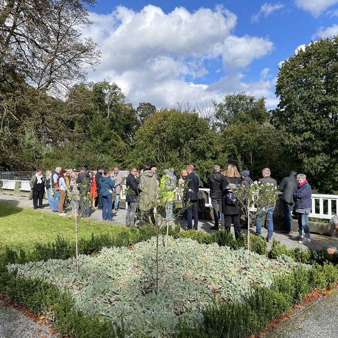Besuchergruppe vor einem Blumenbeet (vergrößerte Bildansicht wird geöffnet)