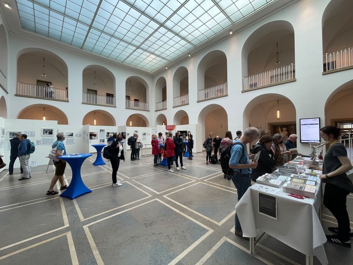 Besuchende am Büchertisch im Lichthof des LWL-Landeshauses (vergrößerte Bildansicht wird geöffnet)