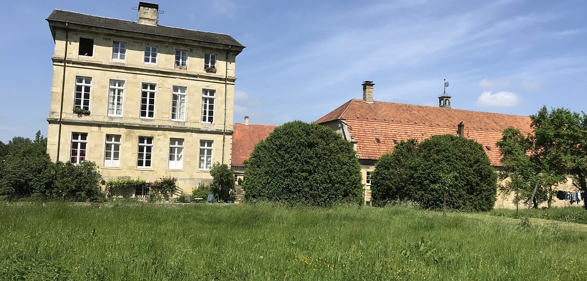 Mächtige, kugelig geschnittene Buchsbäume verdecken die dahinterliegende Gartenbrücke